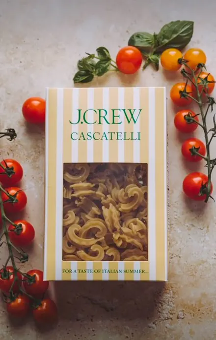 A J.Crew Cascatelli pasta box surrounded by cherry tomatoes and basil