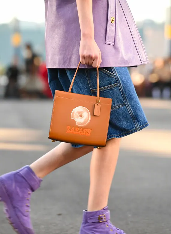 A Coach x Zabar's bagel tote bag carried along a New York street